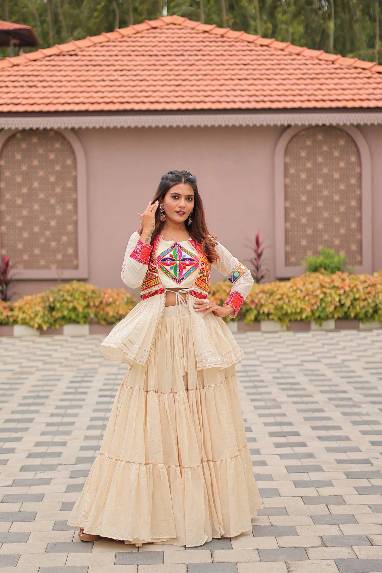 Woman in traditional outfit standing in front of a building with a tiled roof.