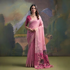 A woman models a vibrant Pink Muga Silk Saree with subtle Resham weaving. The pallu transitions to a darker pink/magenta, featuring intricate purple and green floral Resham threadwork. She wears a matching pink blouse and a gold Kundan necklace.