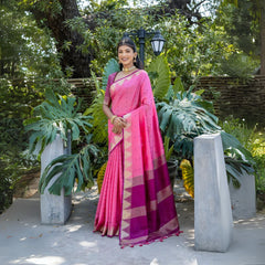 A woman models a vibrant Hot Pink Tussar Silk Saree with small woven motifs. The saree has a gold temple border, and the pallu features wide bands of deep magenta and gold Zari weaving. She wears a magenta blouse and heavy gold Kundan jewelry.