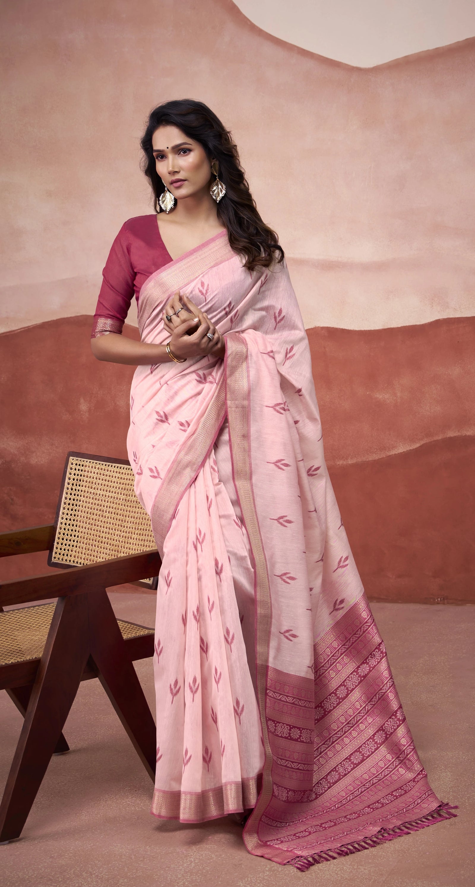 Woman wearing a pink saree with a matching blouse against a beige background