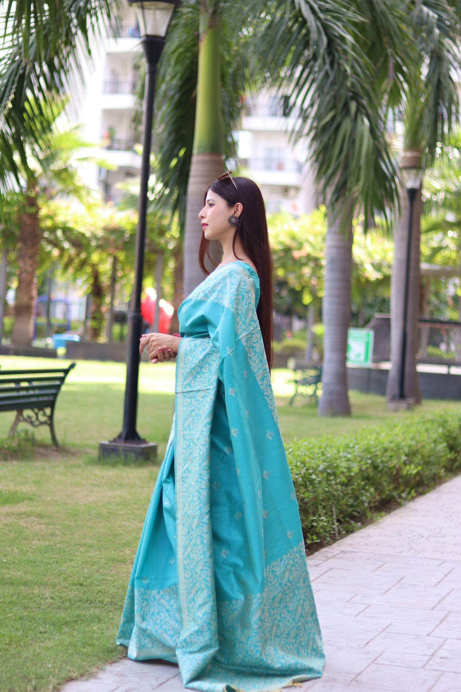 Woman in powder blue saree with traditional weaving design posing elegantly in outdoor setting