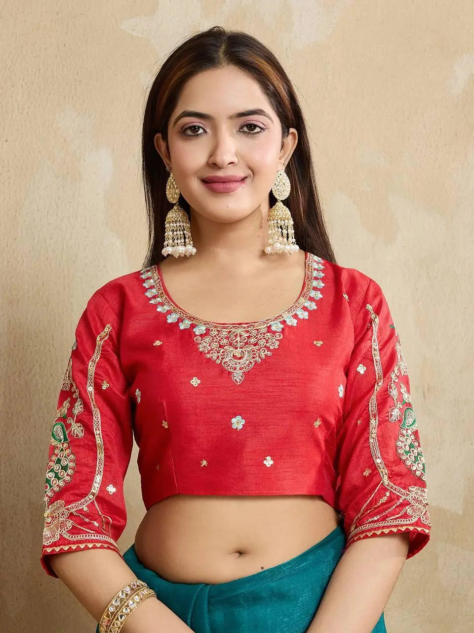 A woman models a vibrant Dark Pink Chiffon Silk Saree with scattered embellishments. The saree has a wide, intricate silver embroidery border. She wears a heavily embroidered dark green blouse and accessorizes with silver jewelry, posing indoors.