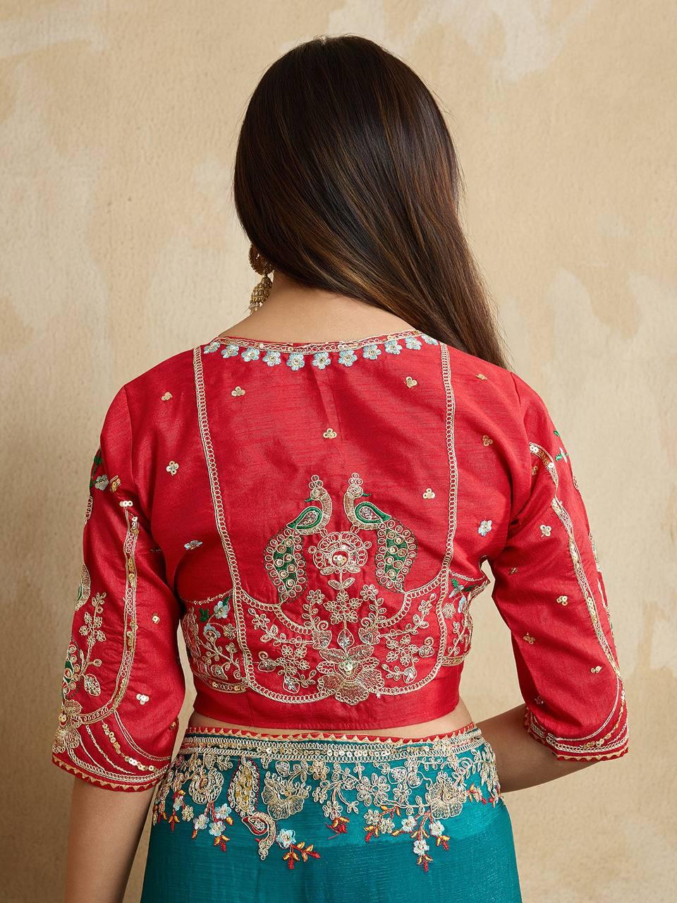 A woman models a vibrant Dark Pink Chiffon Silk Saree with scattered embellishments. The saree has a wide, intricate silver embroidery border. She wears a heavily embroidered dark green blouse and accessorizes with silver jewelry, posing indoors.