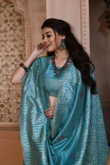 A woman models a striking Sky Blue Banglori Raw Silk Saree. The pallu and border feature dense, traditional Kalamkari-style weaving in a lighter blue metallic thread. She wears a sleeveless blue blouse and heavy oxidized silver or dark gemstone jewelry, posing in an ornate, traditional setting.
