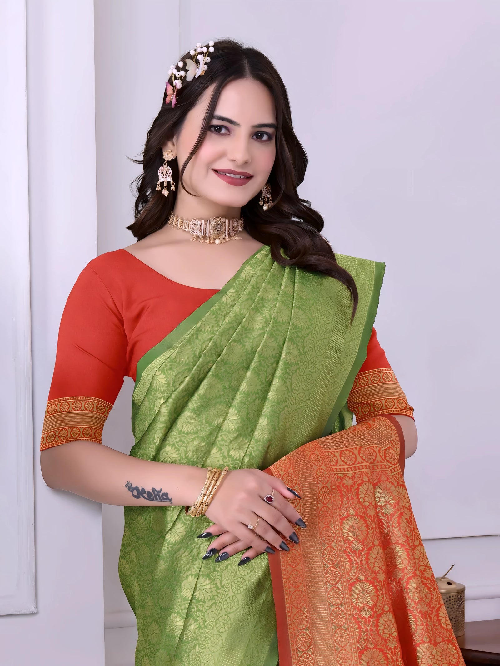 A woman models a striking Green Banarasi Silk Saree with dense tone-on-tone Zari weaving. The pallu provides a dramatic contrast in vibrant red/orange with heavy gold weaving. She wears a red/orange blouse and gold Kundan jewelry.