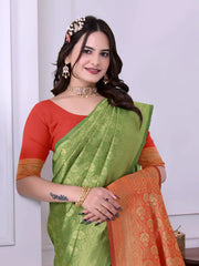 A woman models a striking Green Banarasi Silk Saree with dense tone-on-tone Zari weaving. The pallu provides a dramatic contrast in vibrant red/orange with heavy gold weaving. She wears a red/orange blouse and gold Kundan jewelry.