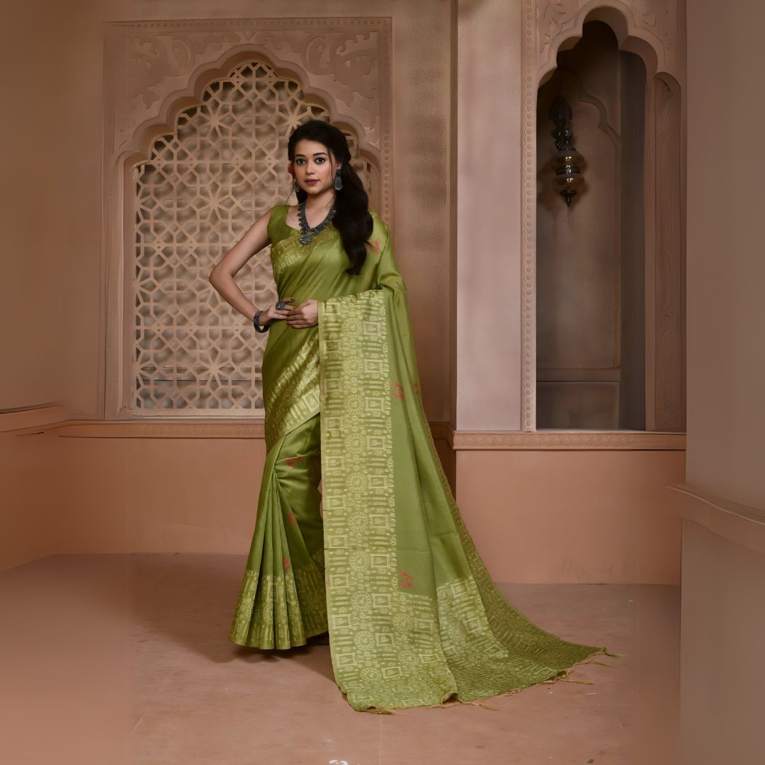 A woman models a striking Pista Green Banglori Raw Silk Saree. The pallu and border feature dense, tone-on-tone Kalamkari-style weaving in gold Zari. She wears a sleeveless green blouse and heavy oxidized silver or dark gemstone jewelry, posing in an ornate, traditional setting.