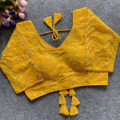 zYellow designer blouse with silver thread embroidery, deep back neckline, and stylish tassel tie detailing.