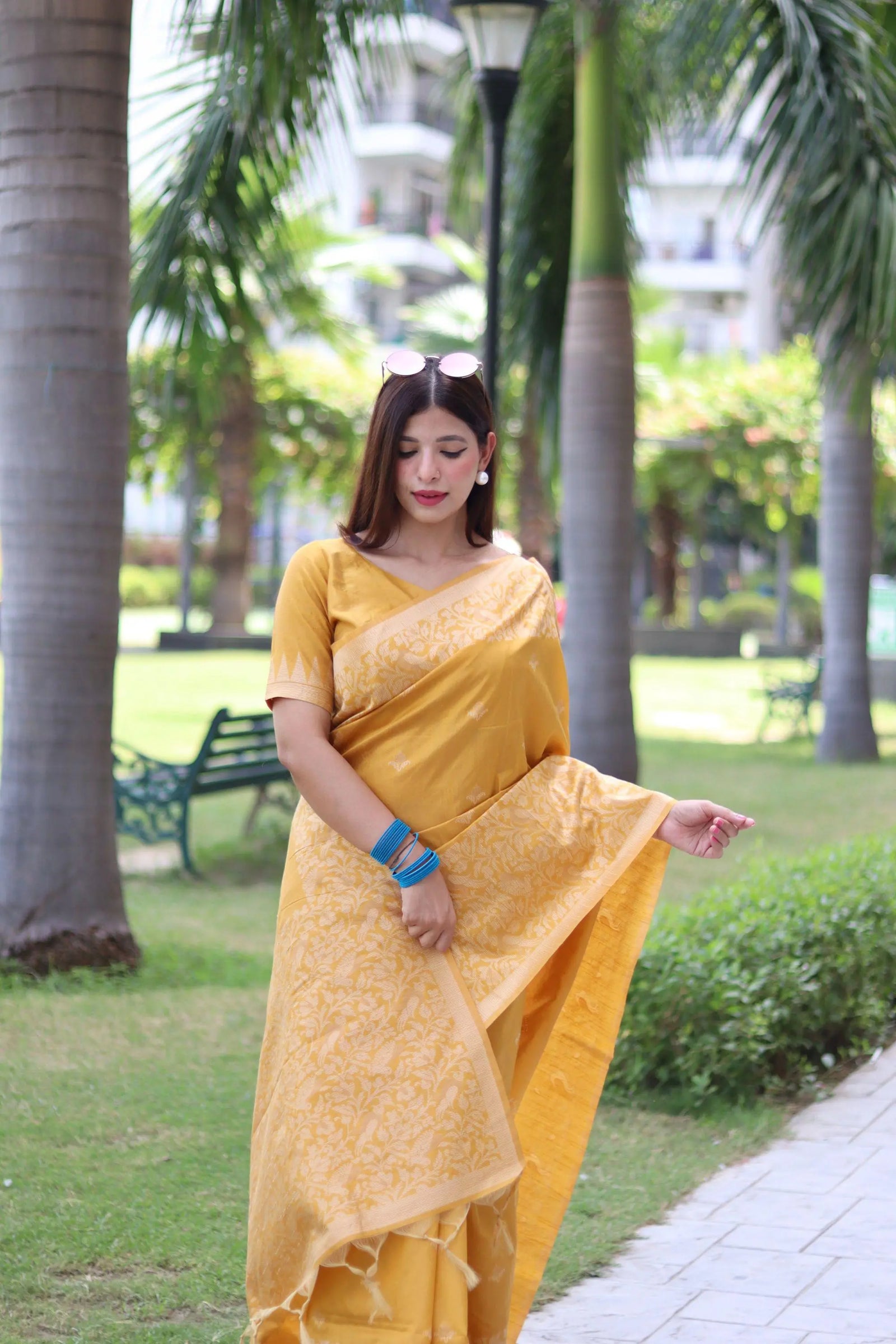 Woman wearing yellow traditional weaving saree posing gracefully in a lush garden setting