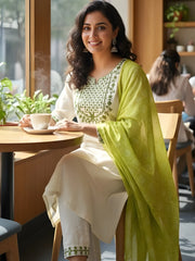 Woman sitting at a table in a cafe wearing a traditional outfit with a green dupatta.