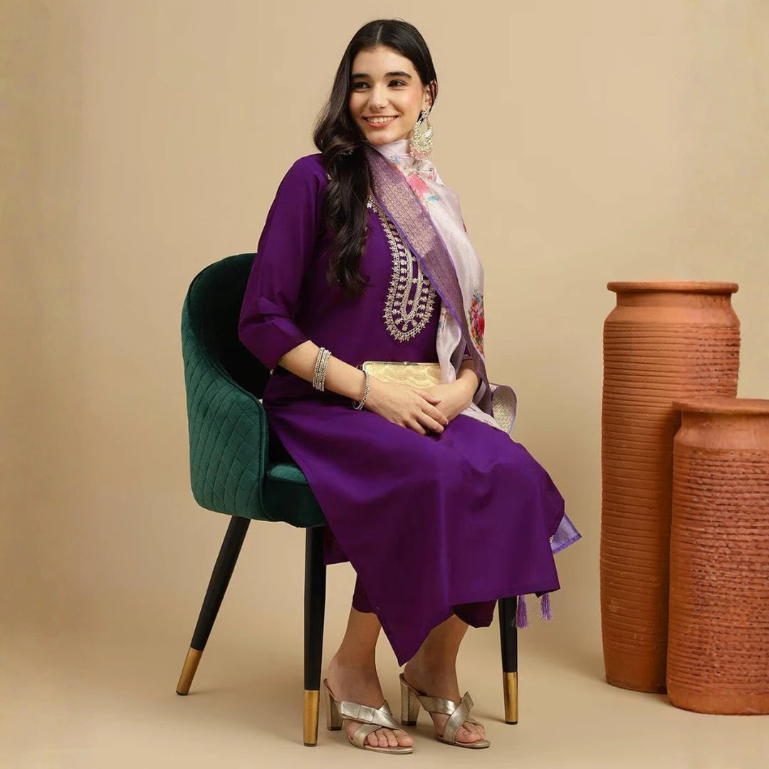Woman in a purple outfit sitting on a green chair with terracotta pots in the background