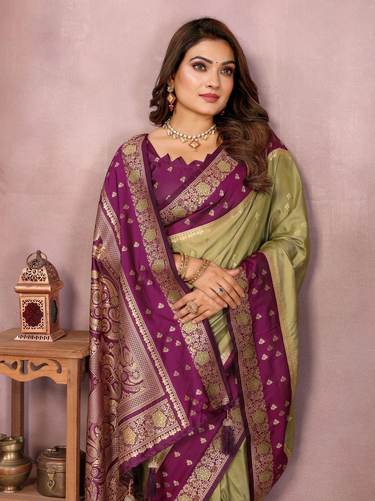 Woman wearing a traditional purple and green saree with a pink background