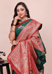 Woman wearing a green and red saree with intricate patterns on a beige background