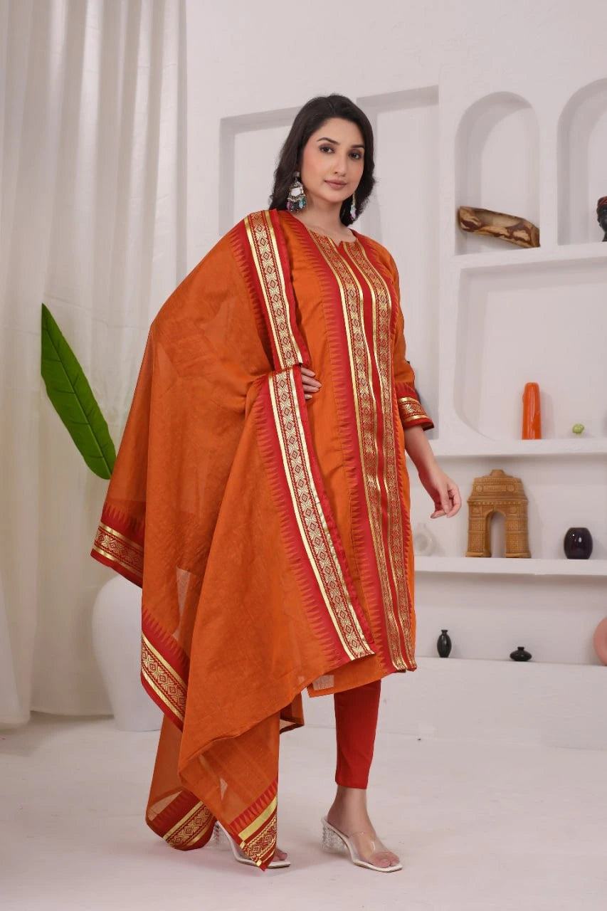 Woman wearing an orange traditional outfit with gold details in a minimalistic setting.
