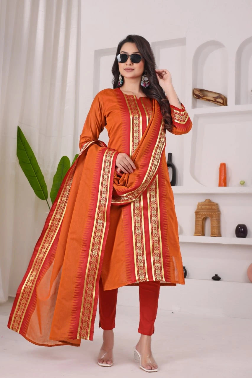 Woman wearing an orange traditional outfit with a dupatta in a minimalistic room.