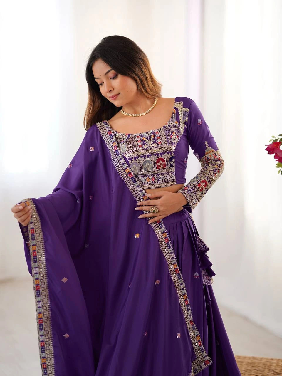 Woman wearing a purple embroidered traditional outfit with a white background