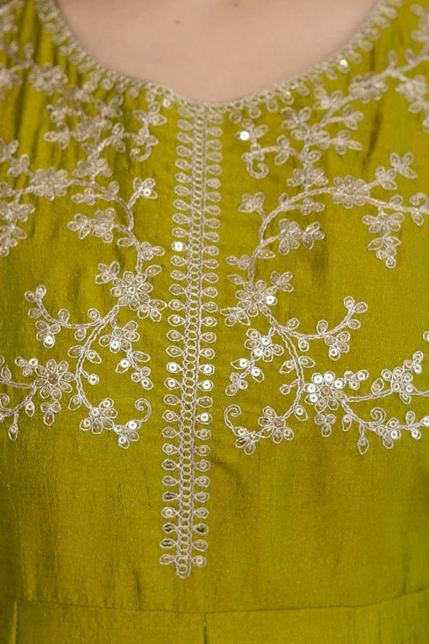 Green dress with intricate white embroidery on a plain background