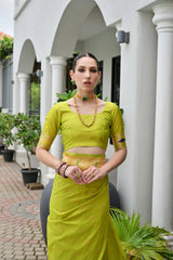 Woman in a bright green traditional outfit standing in front of a white building with columns.