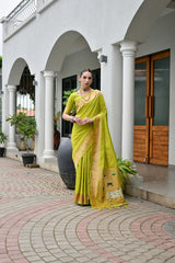 Woman in a yellow saree standing in front of a building with columns.