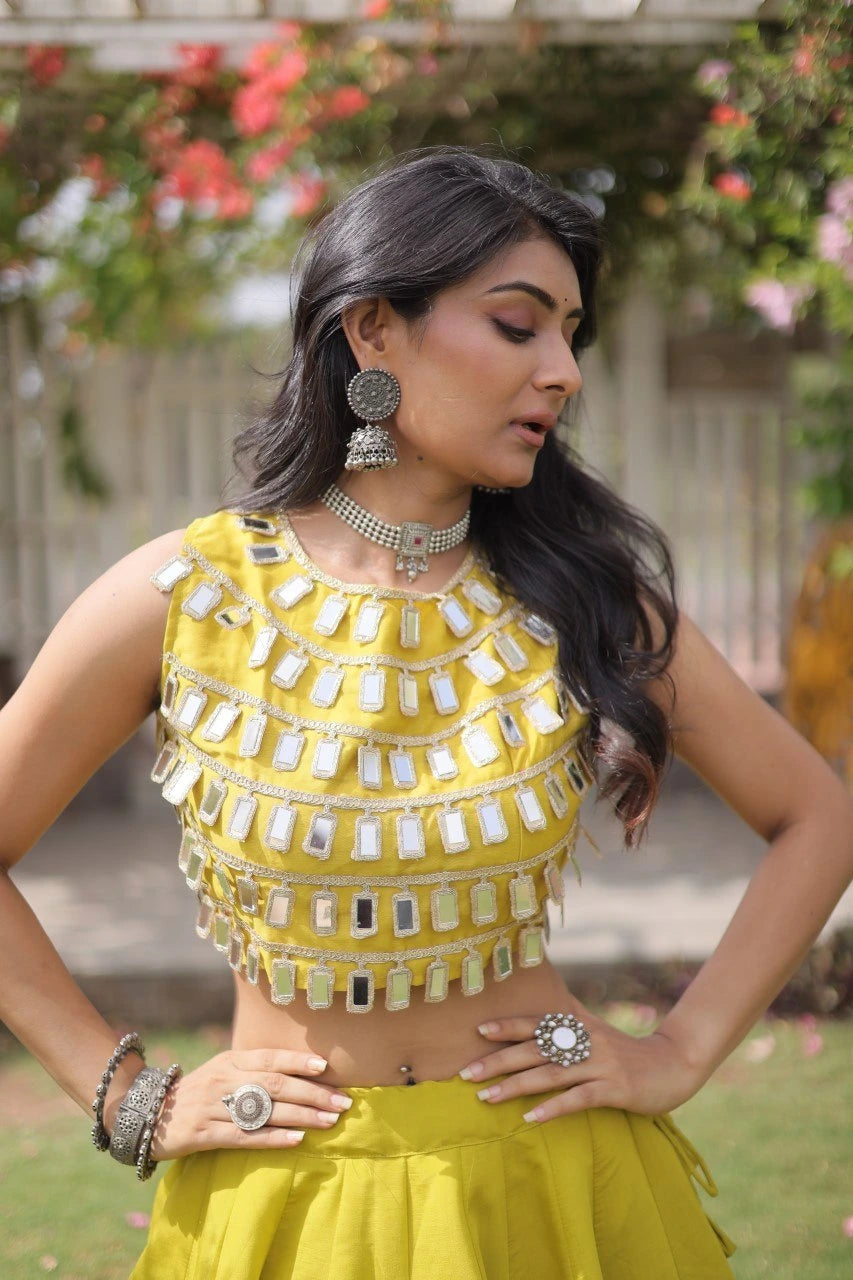 Elegant yellow lehenga choli featuring a sleeveless mirror work blouse and a flared skirt with bold golden polka dot motifs.