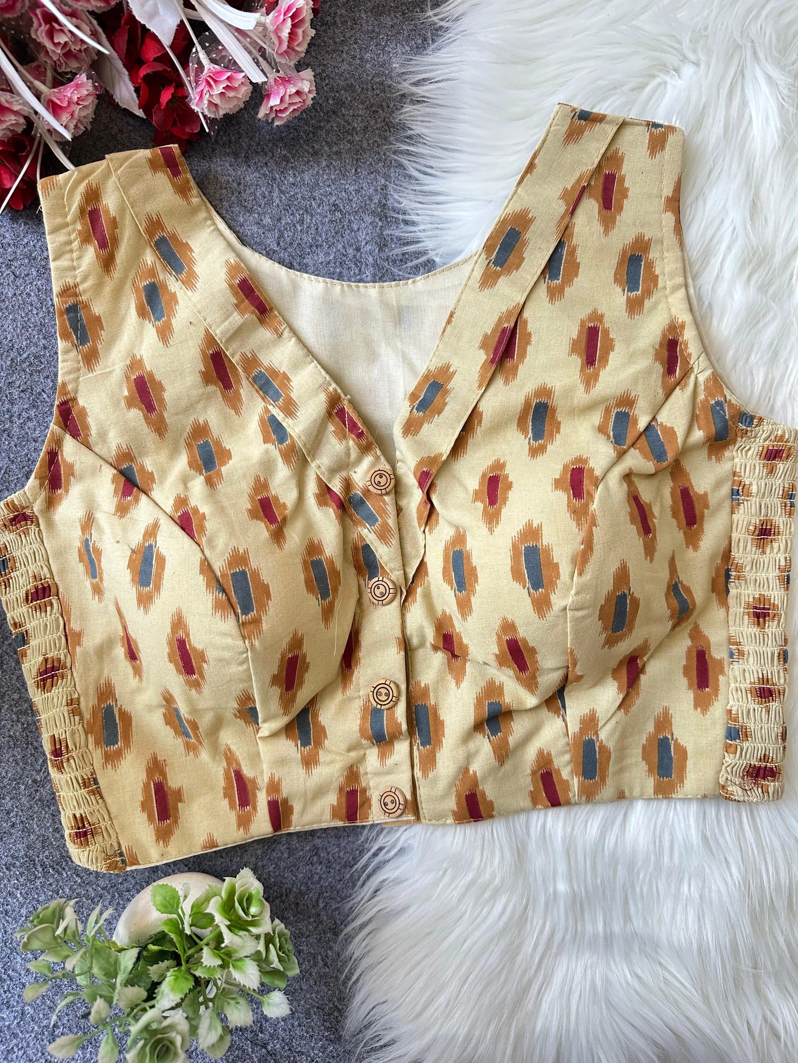 Beige patterned blouse with buttons on a textured surface
