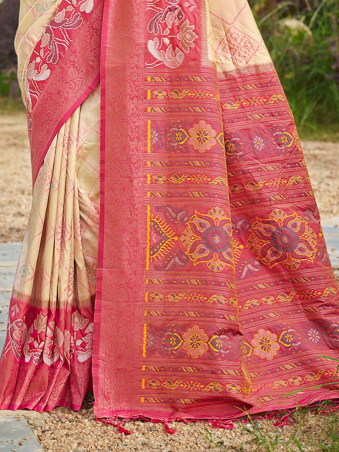 Traditional pink and beige saree with intricate patterns on a natural background