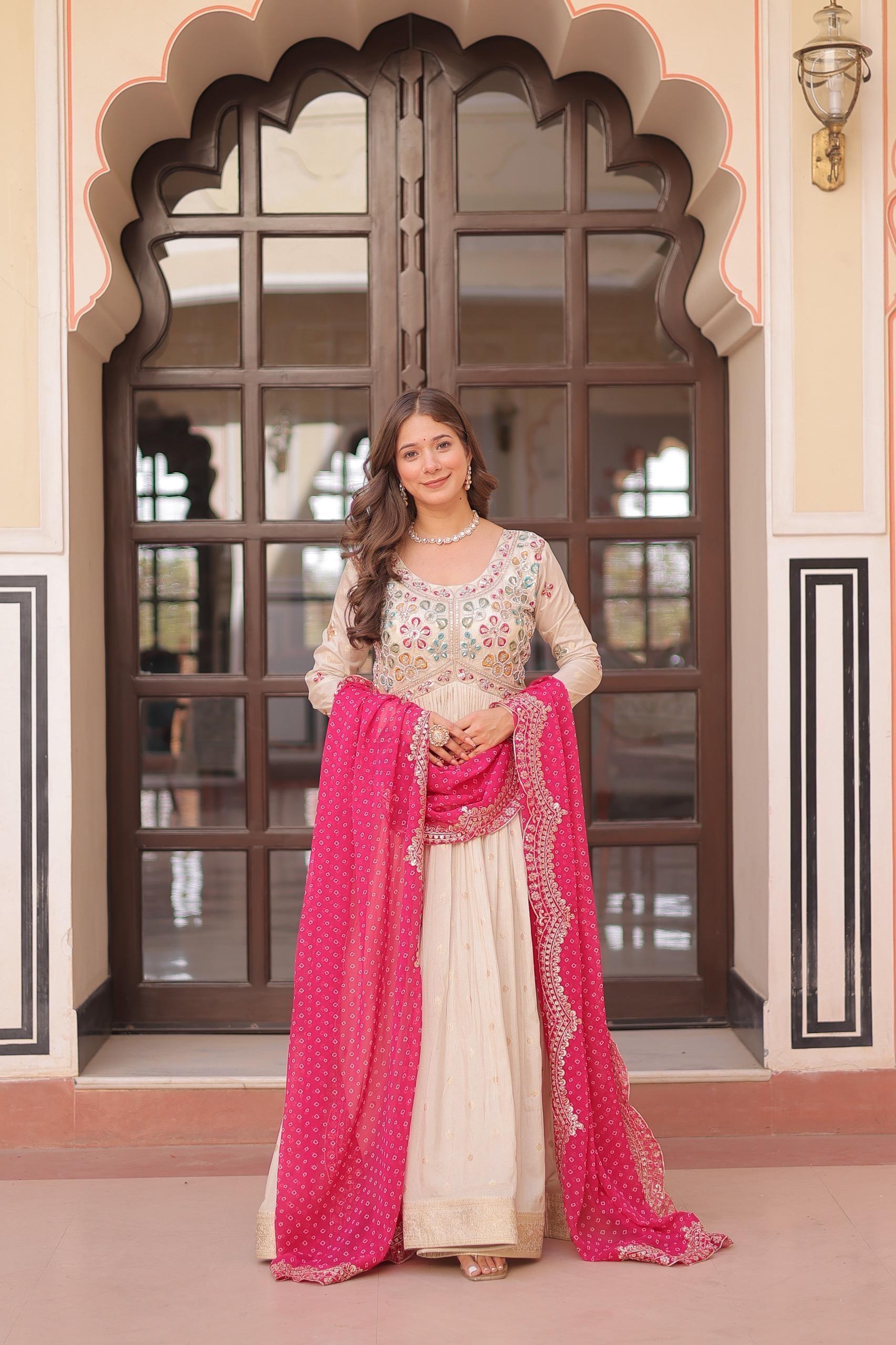 Woman in traditional outfit with pink dupatta standing in front of decorative door