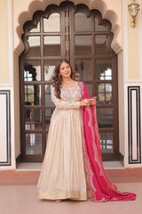 Woman in a traditional outfit with a pink dupatta standing in front of an ornate door.