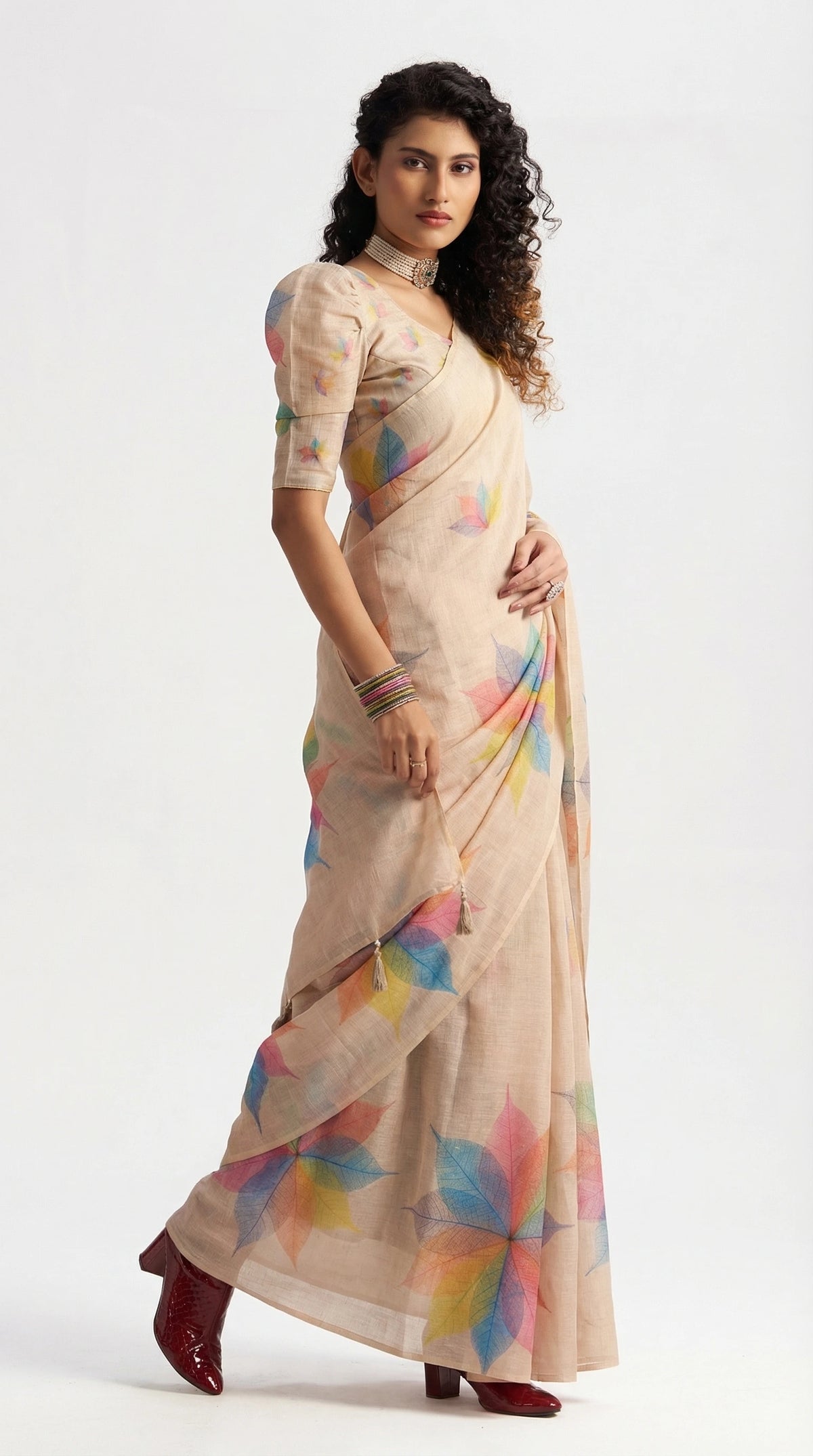 Woman wearing a beige saree with colorful patterns on a white background