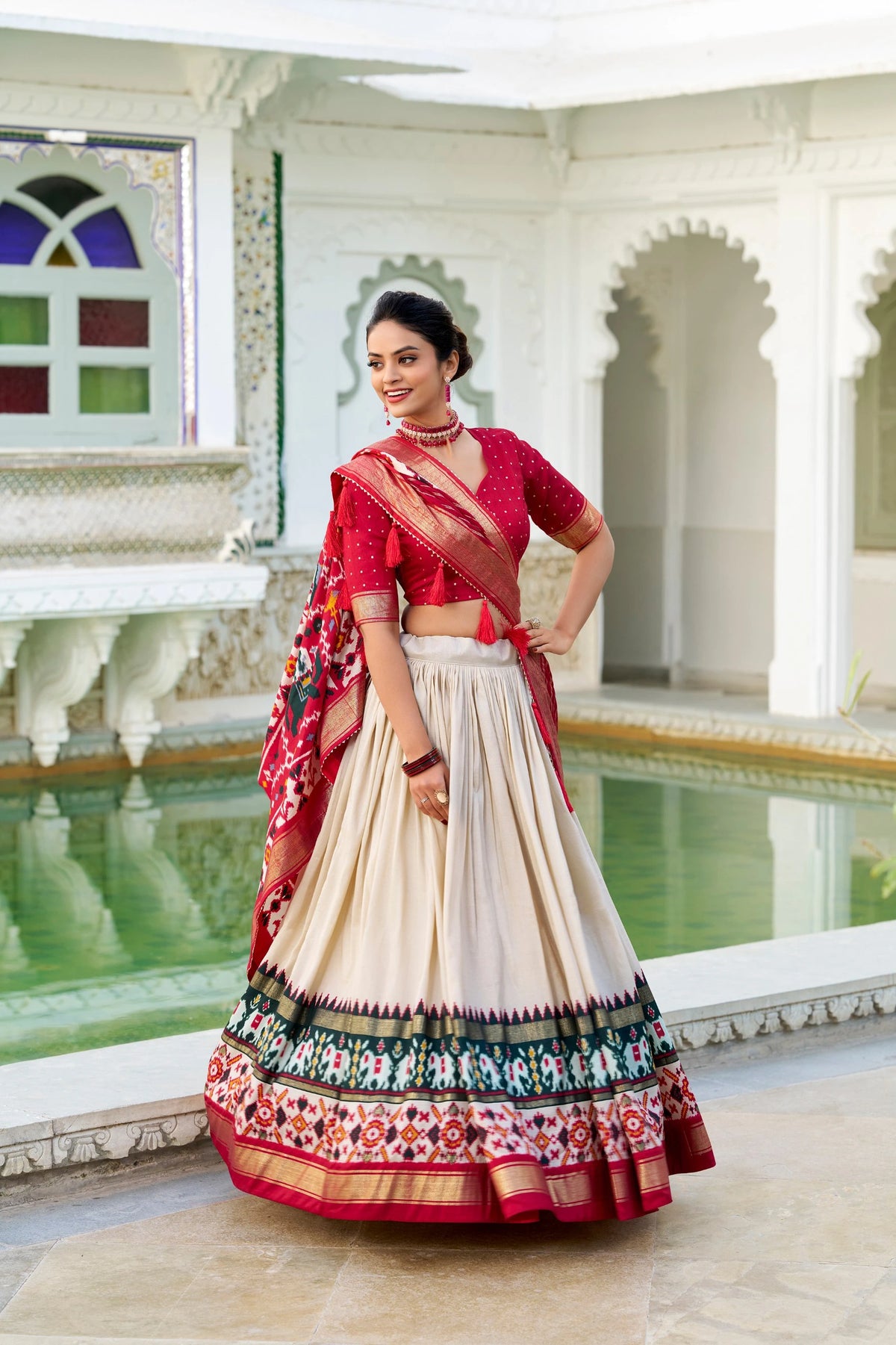 Woman in a traditional outfit with a colorful sari in an elegant indoor setting.