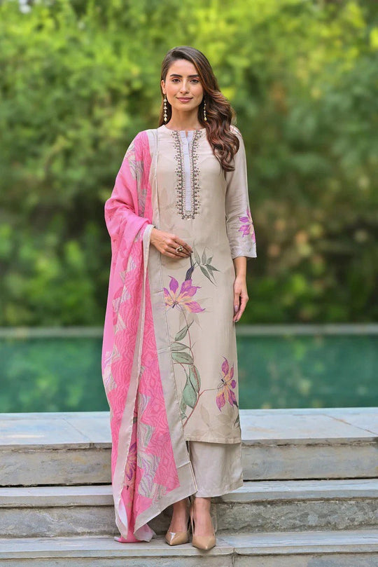 Woman in a traditional outfit with floral patterns standing outdoors.