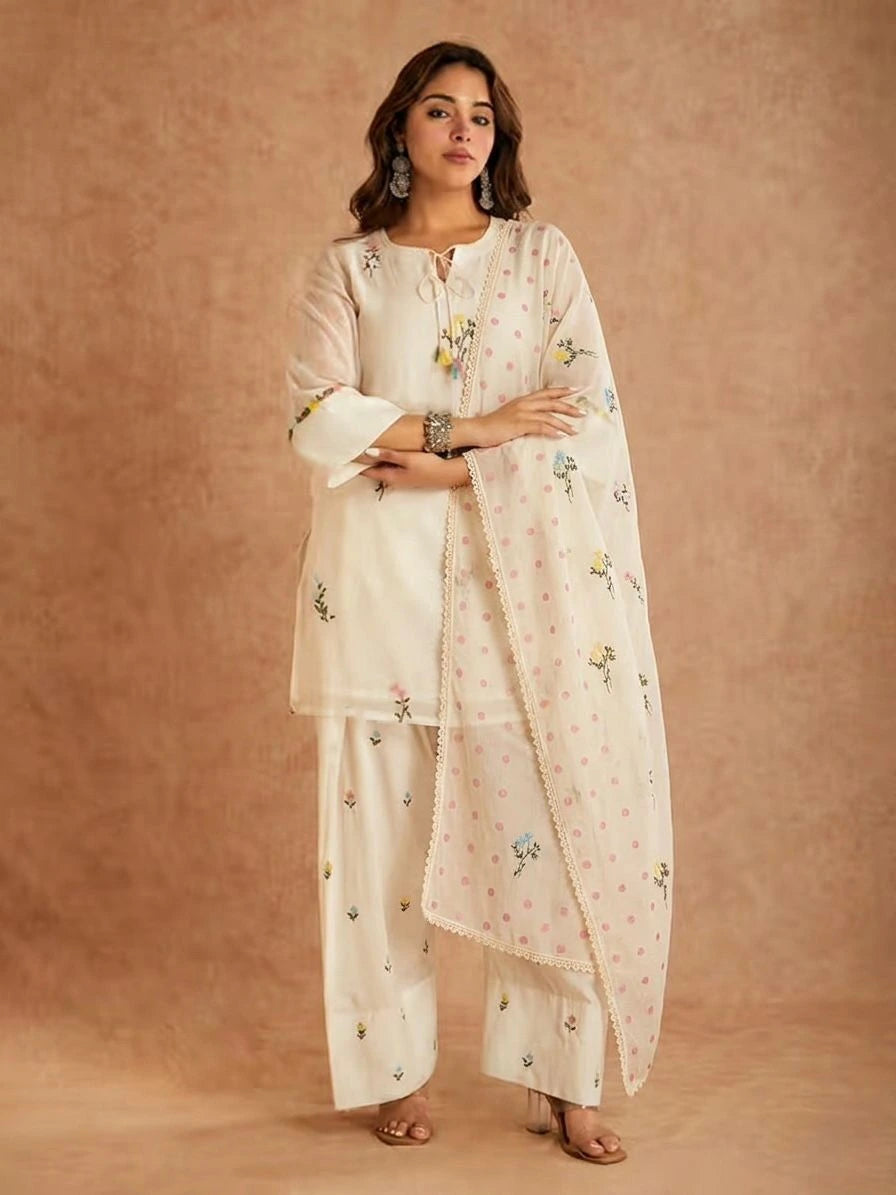 Woman wearing a white embroidered outfit with a dupatta on a beige background