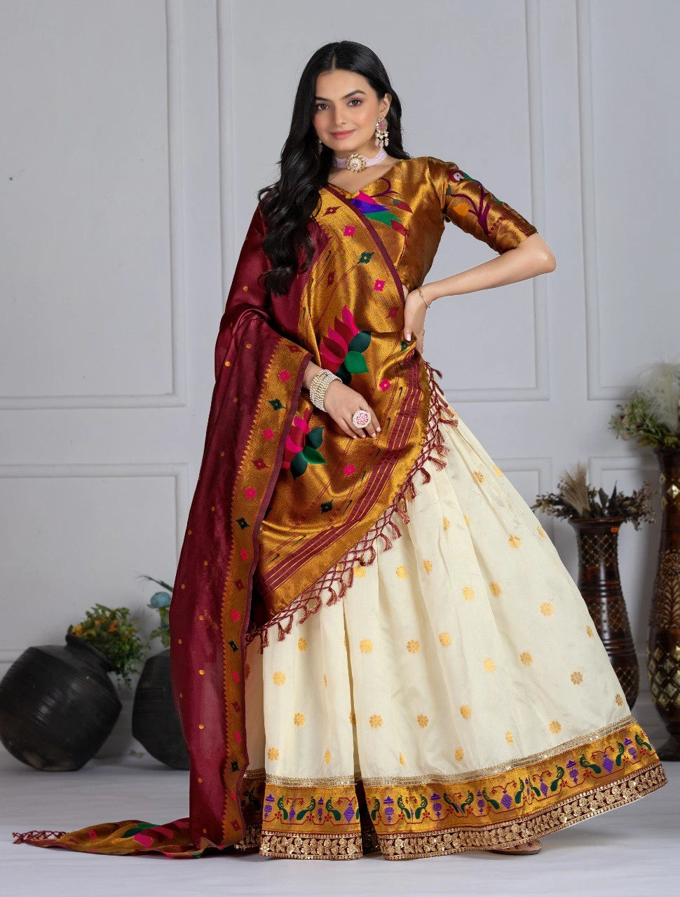 Woman wearing a traditional saree with a white blouse and a colorful border against a neutral background