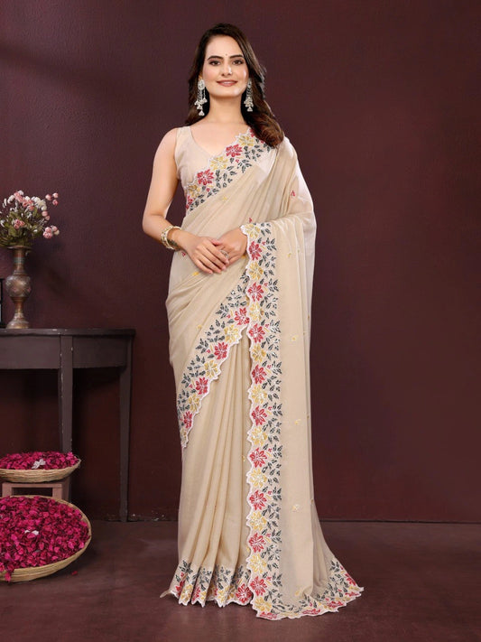 Woman wearing a beige saree with floral patterns against a dark background