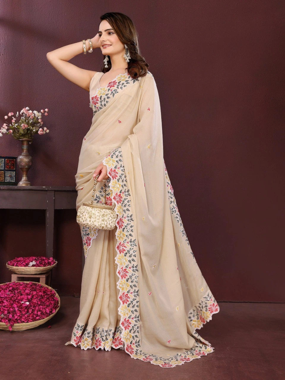Woman wearing a beige saree with floral patterns against a brown background