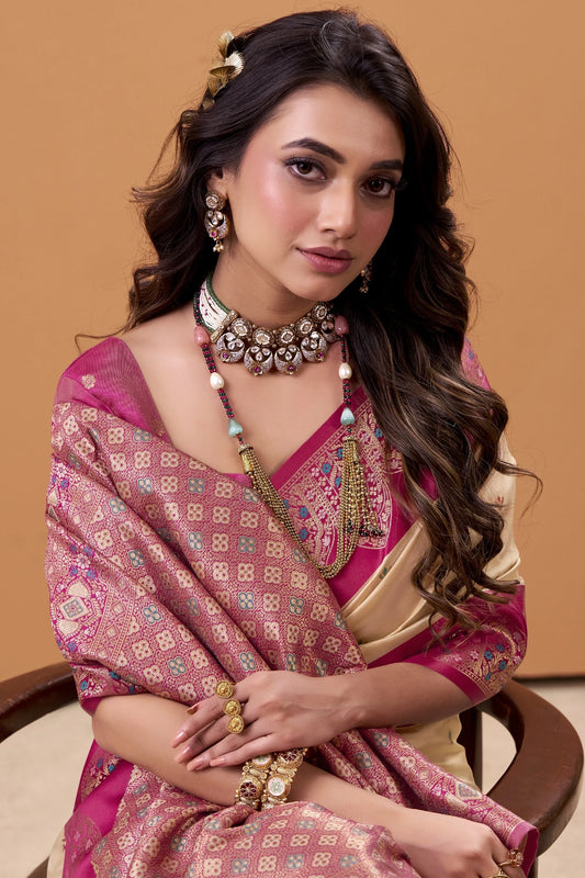 Woman in traditional pink and gold saree with jewelry against a beige background