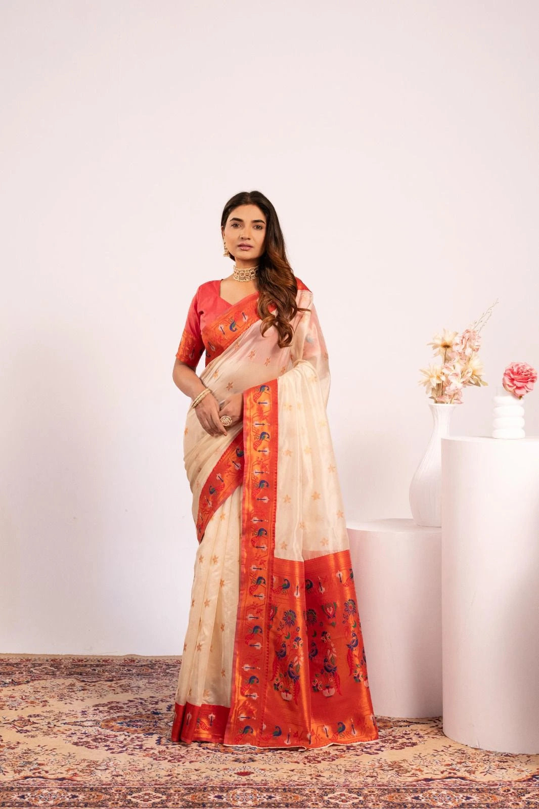 Woman wearing a saree with a red and beige pattern on a white background