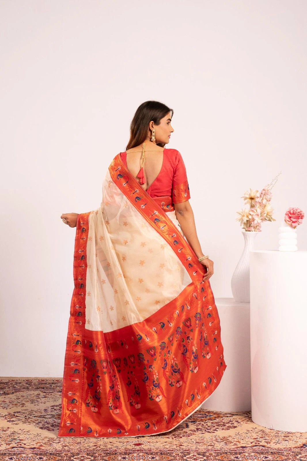 Woman wearing a red and beige saree with a white background