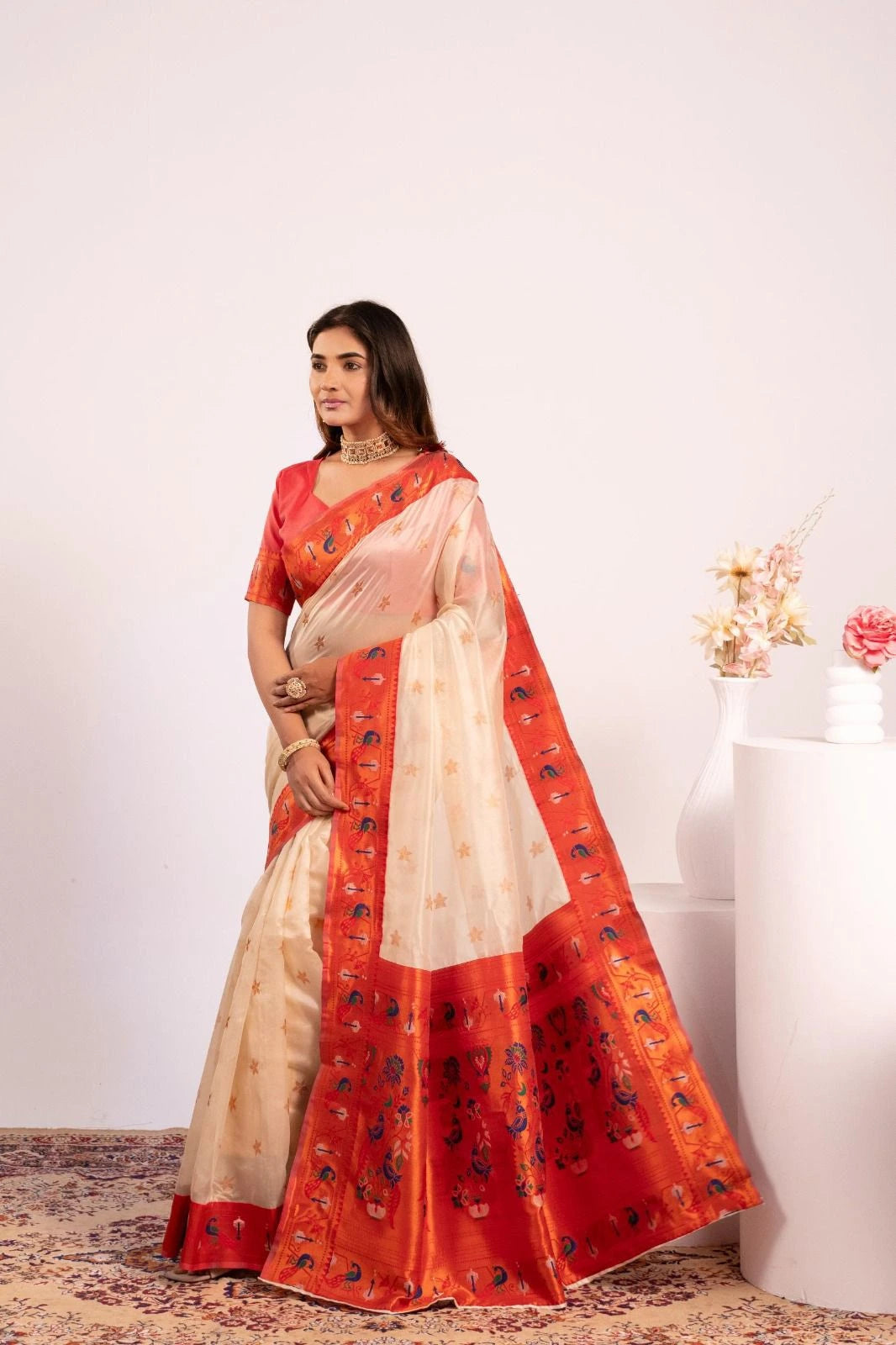 Woman wearing a red and beige saree with a white background