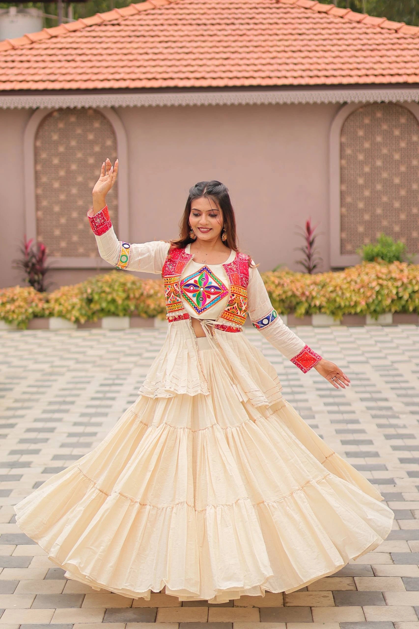 Woman in traditional outfit with colorful patterns standing in front of a building.