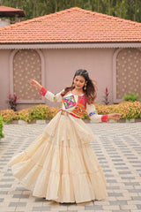 Woman in traditional outfit with colorful blouse and beige skirt standing on a paved area.