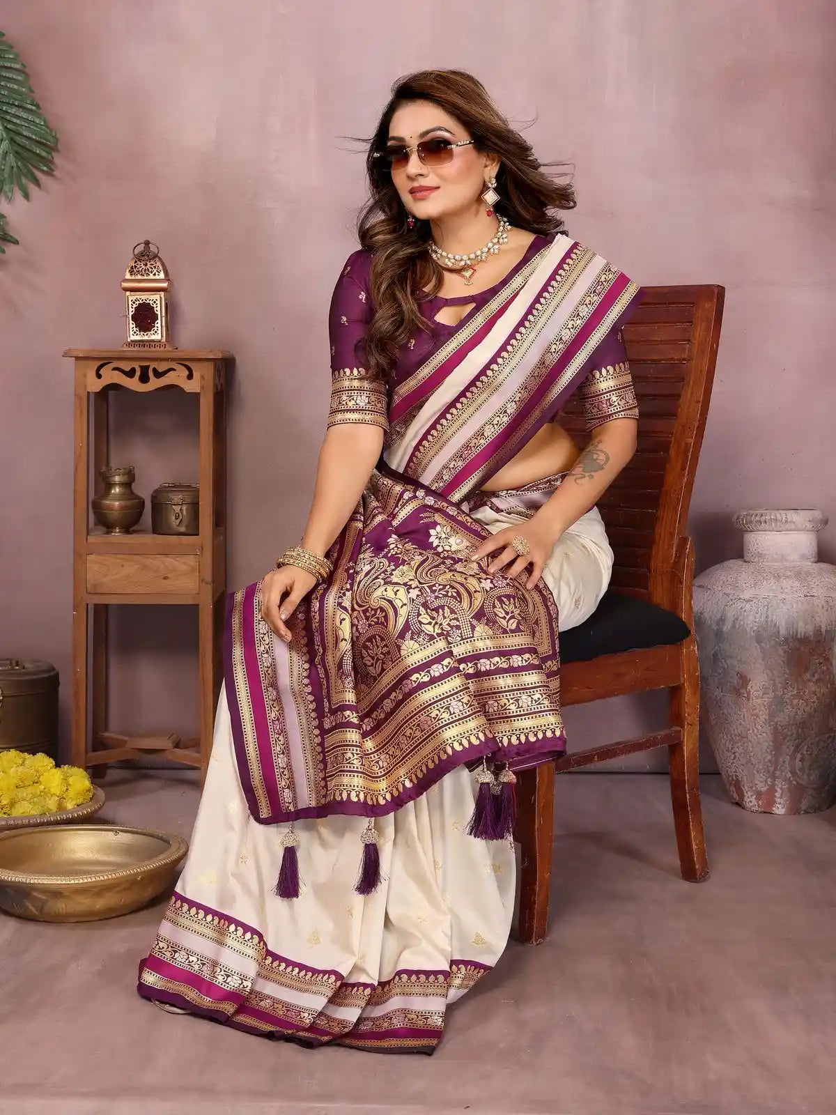 Woman in a traditional saree sitting on a chair with a decorative background