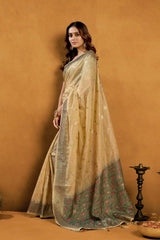 Woman wearing a beige saree with a subtle pattern against an orange background