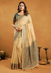 Woman wearing a beige saree with floral patterns on a brown background