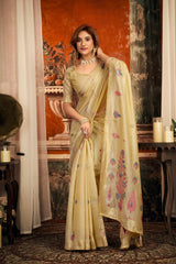 Woman in a traditional beige saree with floral patterns in an indoor setting.