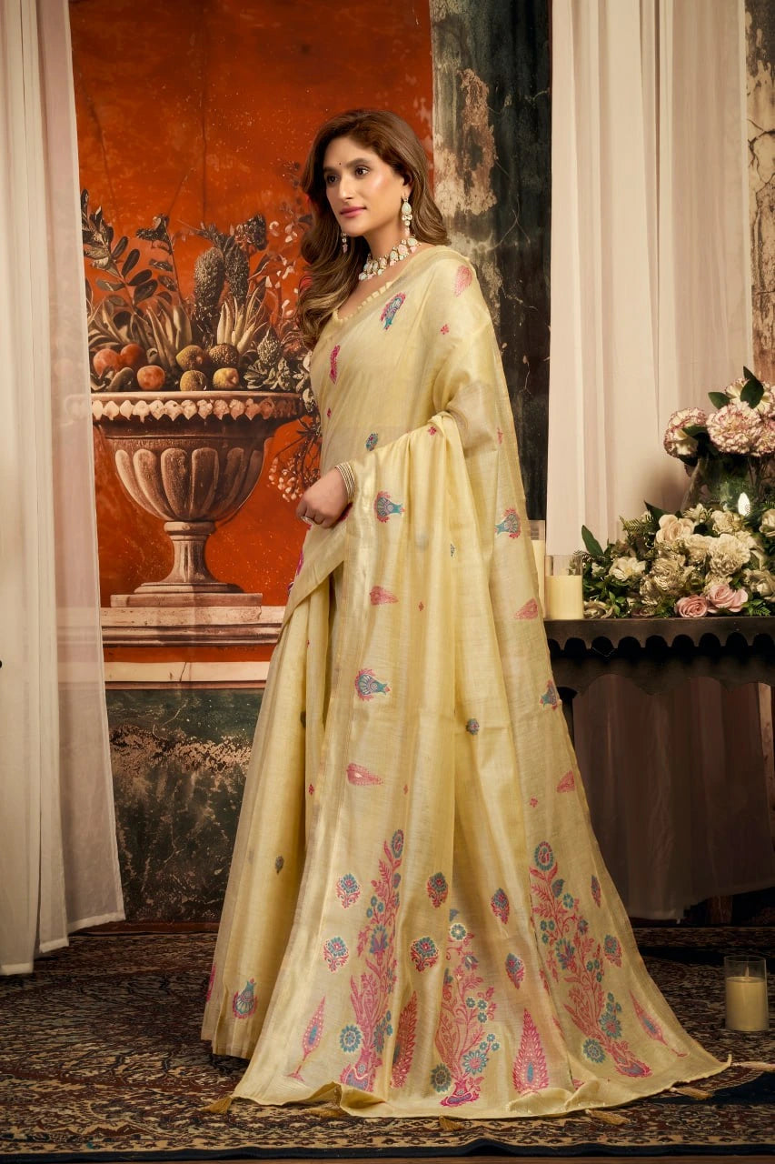 Woman in a light-colored saree with floral patterns in an elegant indoor setting.