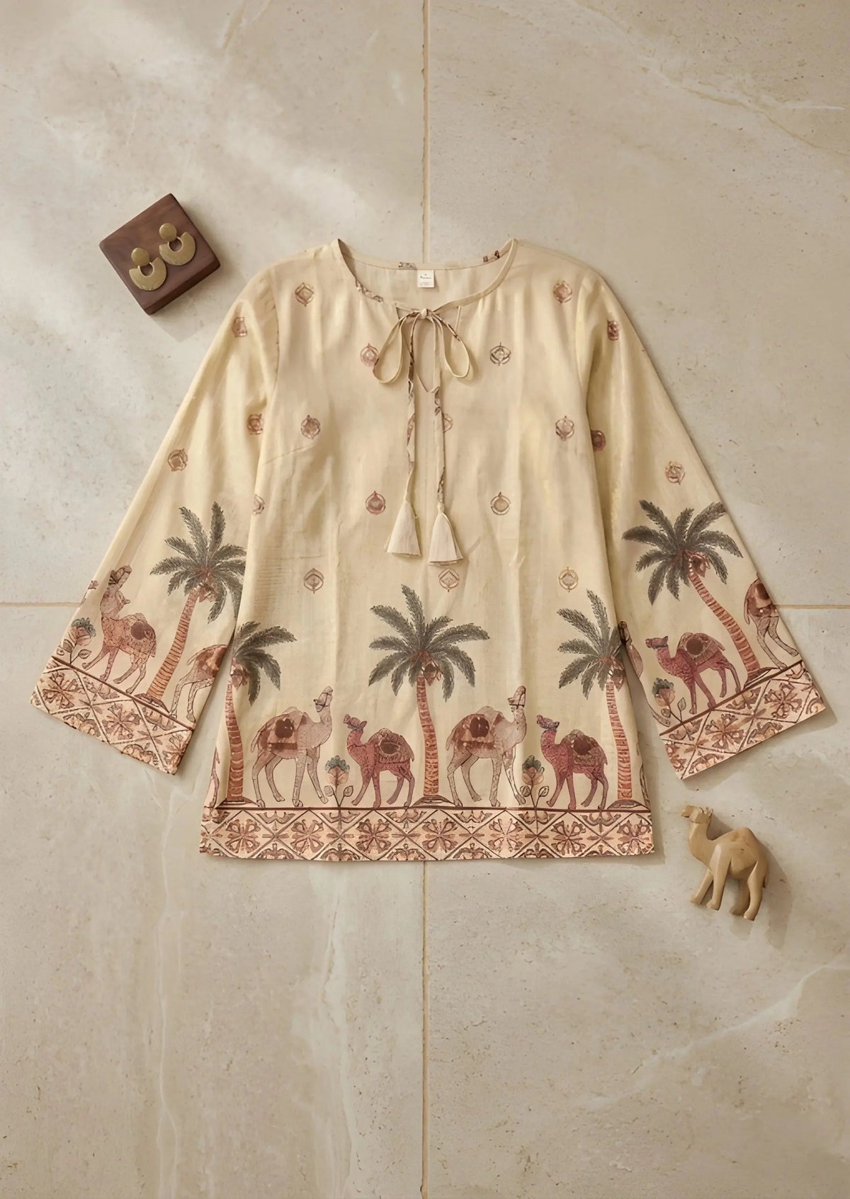 Beige blouse with camel and palm tree pattern on a beige tiled background