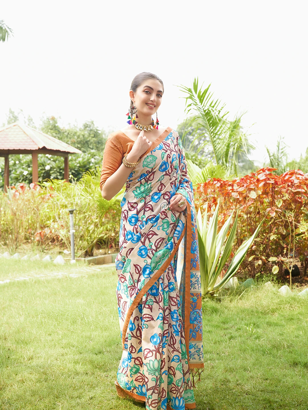 Women's beige floral saree with intricate copper brown woven border and tassel pallu for festive occasions.