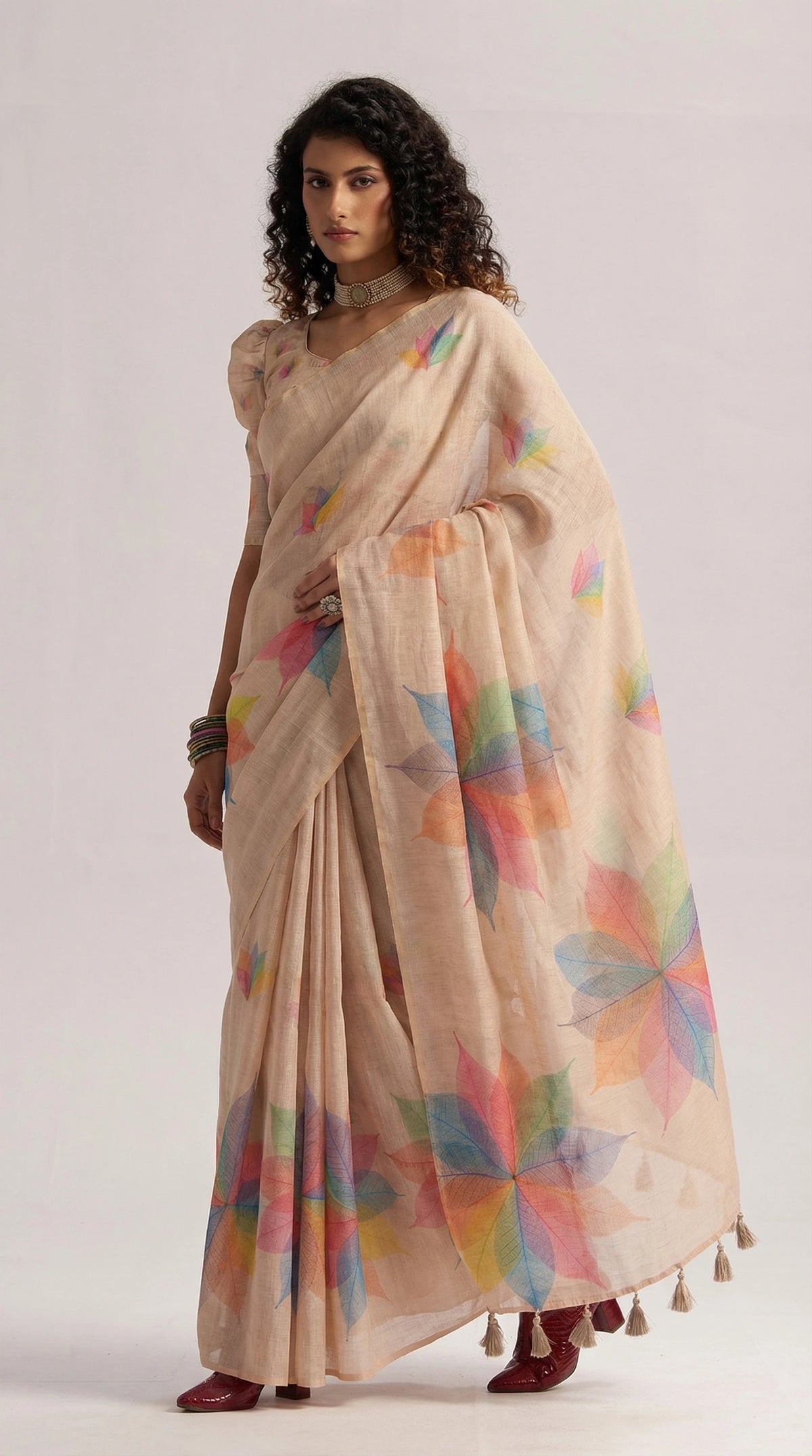 Woman wearing a beige saree with colorful patterns on a white background