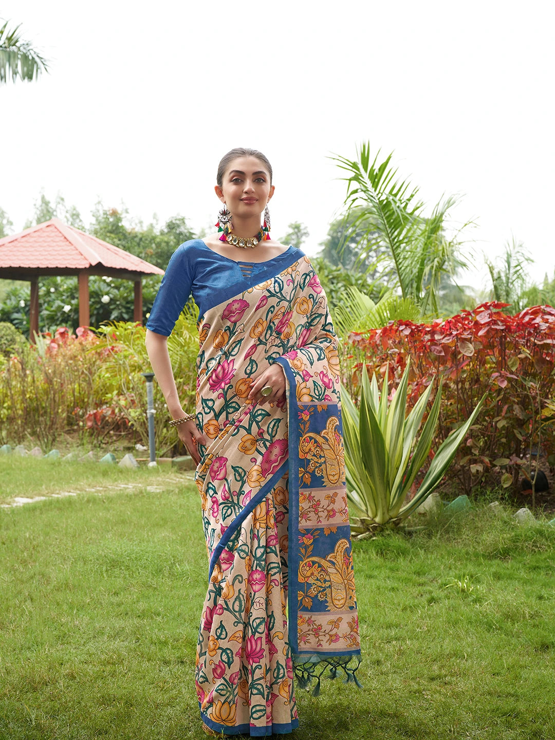 Women's beige floral saree with intricate blue woven border and tassel pallu for festive occasions.